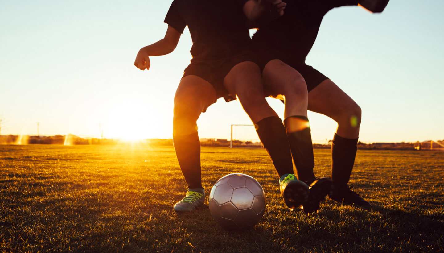 To barn som spiller fotball i solnedgangen