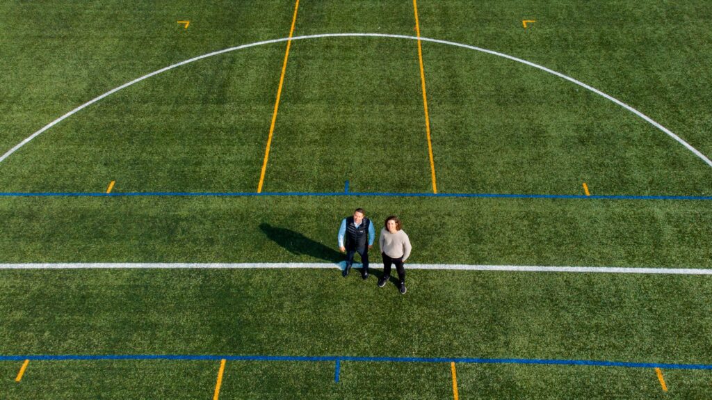 Dronebilde av to mennesker på en fotballbane